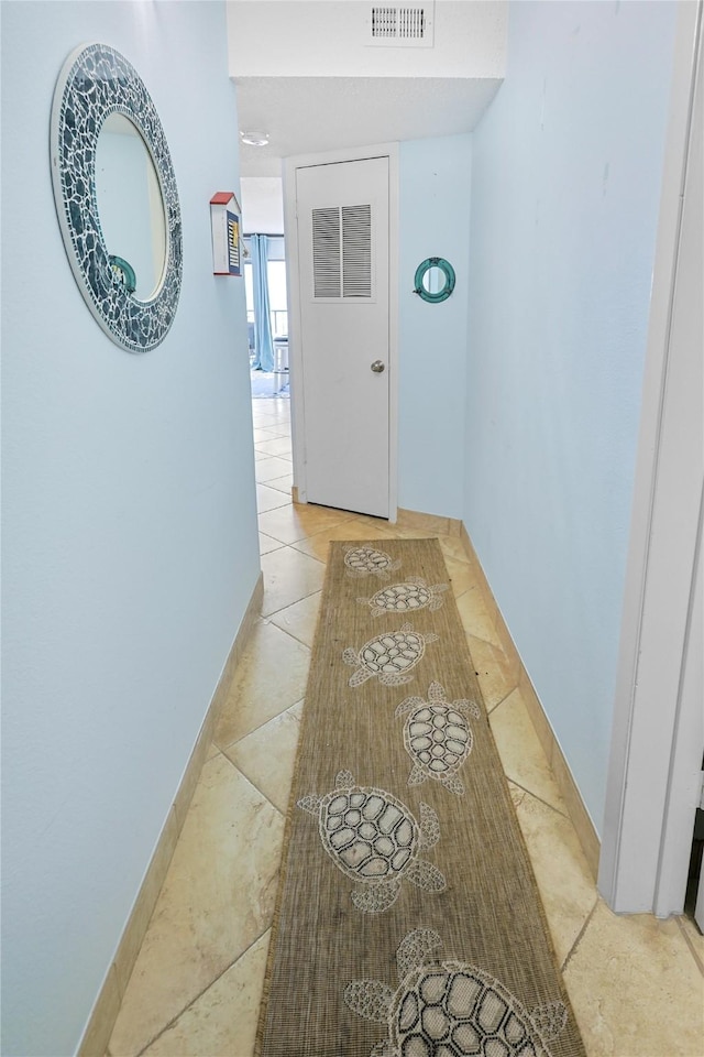 hall featuring light tile patterned flooring and visible vents