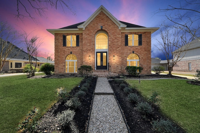 view of front of property featuring brick siding, french doors, and a front yard