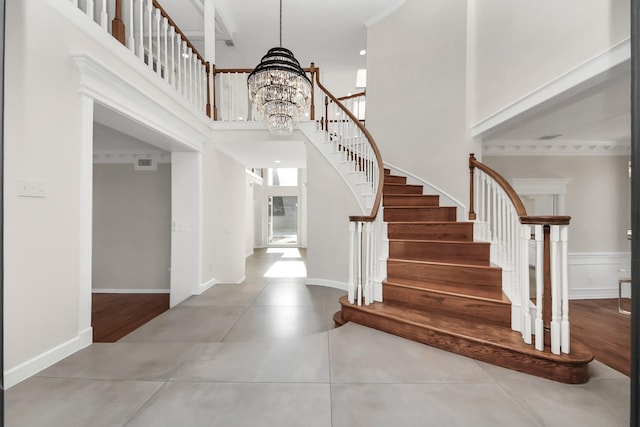 foyer entrance featuring visible vents, a high ceiling, an inviting chandelier, baseboards, and stairs