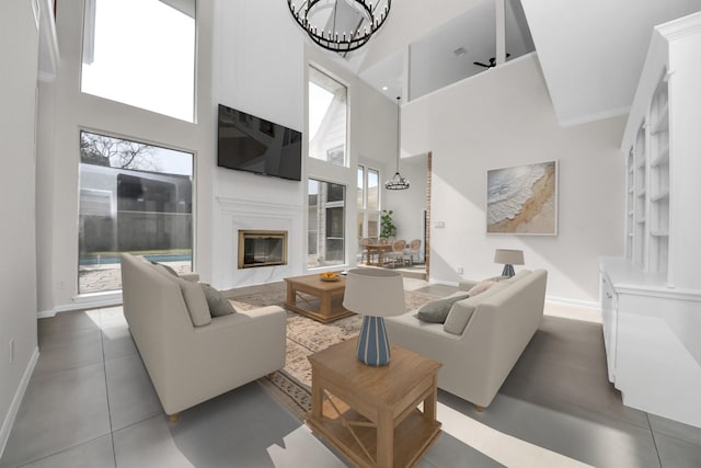 living area with a glass covered fireplace, plenty of natural light, and a towering ceiling