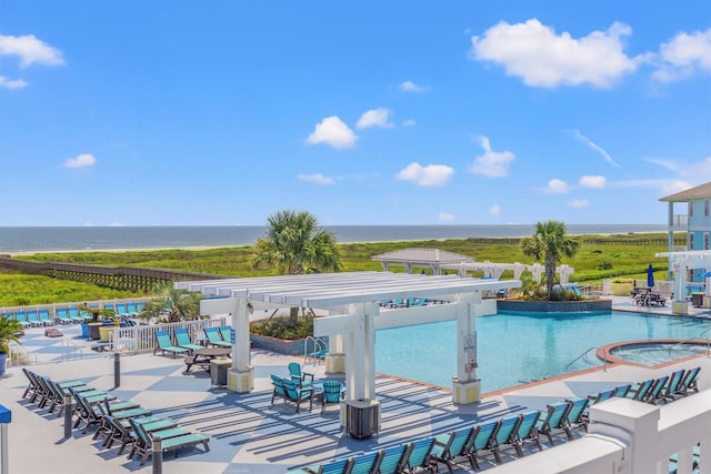 community pool with a patio, fence, and a water view