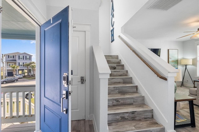 entryway featuring a healthy amount of sunlight, stairs, ceiling fan, and wood finished floors