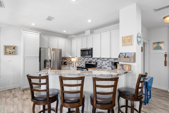 kitchen with visible vents, backsplash, a peninsula, and stainless steel appliances