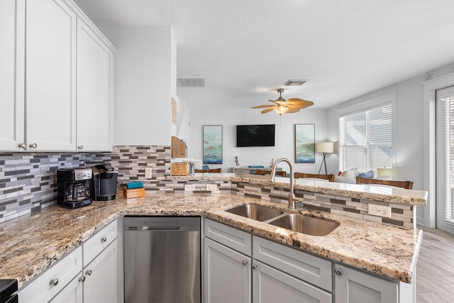 kitchen featuring tasteful backsplash, visible vents, dishwasher, a peninsula, and a sink