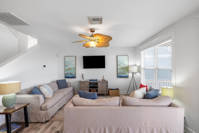 living area featuring visible vents, baseboards, light wood-style flooring, and a ceiling fan