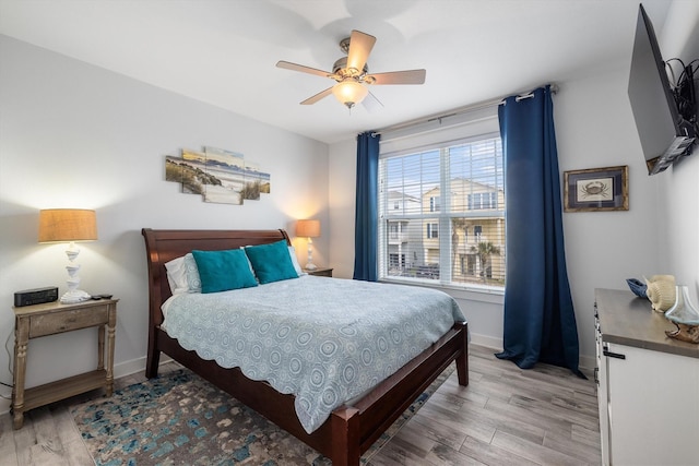 bedroom featuring light wood-style flooring, a ceiling fan, and baseboards