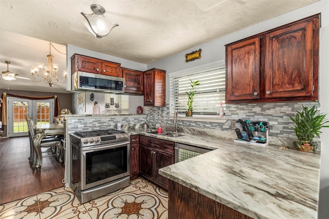 kitchen featuring a sink, a peninsula, appliances with stainless steel finishes, and a wealth of natural light