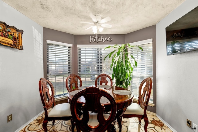 dining space featuring baseboards, plenty of natural light, a textured ceiling, and a ceiling fan