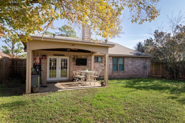 back of house with french doors, a chimney, a fenced backyard, and brick siding