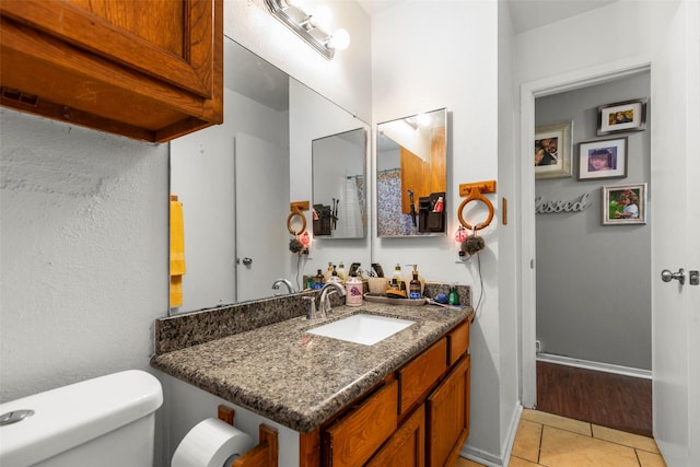 bathroom with vanity, baseboards, tile patterned floors, and toilet