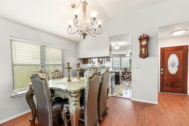 dining space featuring baseboards, vaulted ceiling, wood finished floors, and an inviting chandelier