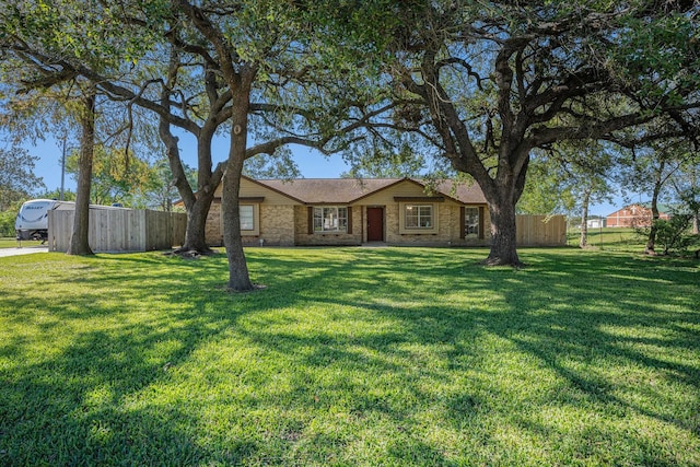 view of front of house with brick siding, a front lawn, and fence