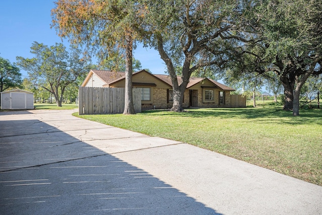 view of front of home featuring a front lawn, fence, a storage shed, an outdoor structure, and brick siding