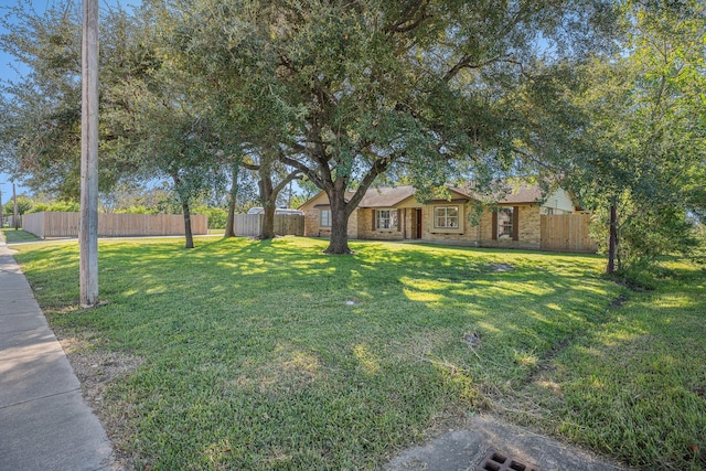 view of front facade with a front lawn, fence, and brick siding