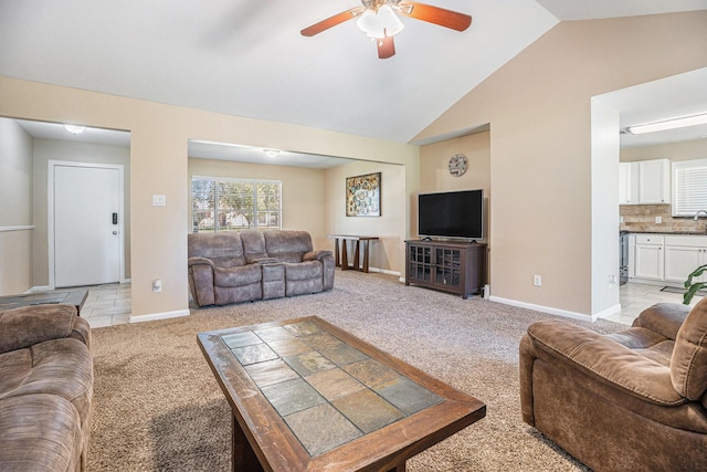 living room with light colored carpet, ceiling fan, baseboards, and vaulted ceiling