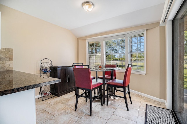 dining space with baseboards, light tile patterned flooring, and vaulted ceiling