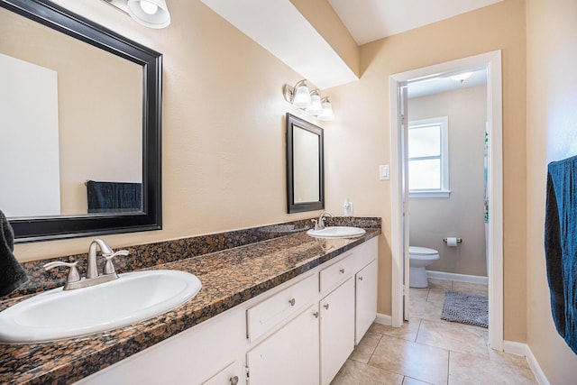 bathroom with tile patterned flooring, double vanity, toilet, and a sink