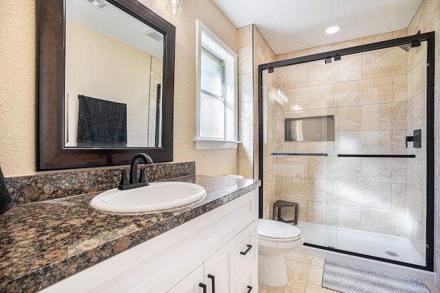 bathroom featuring visible vents, a stall shower, toilet, and vanity