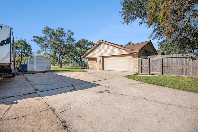 view of side of property with brick siding, fence, concrete driveway, a storage shed, and a gate