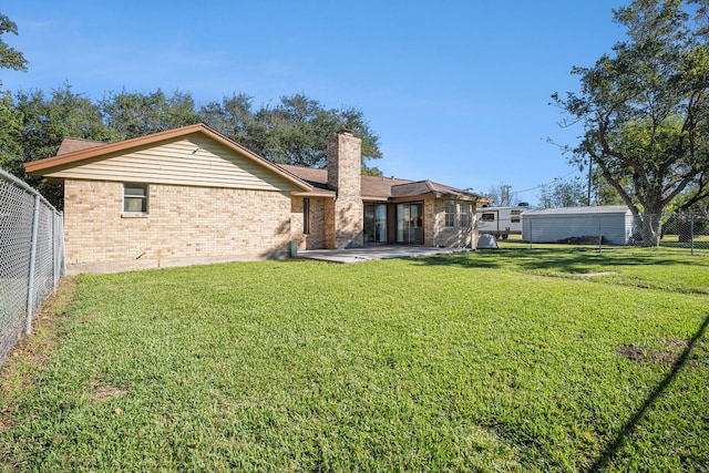 back of house featuring brick siding, a patio area, a lawn, and fence