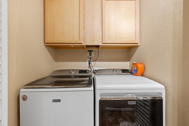 laundry area with cabinet space, independent washer and dryer, and a textured wall