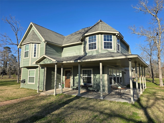 view of front of house featuring a patio, roof with shingles, and a front yard