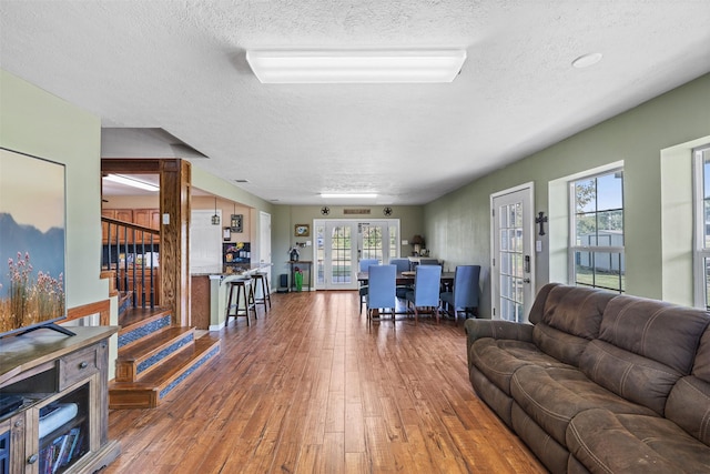 living area with french doors, wood-type flooring, a textured ceiling, and stairs