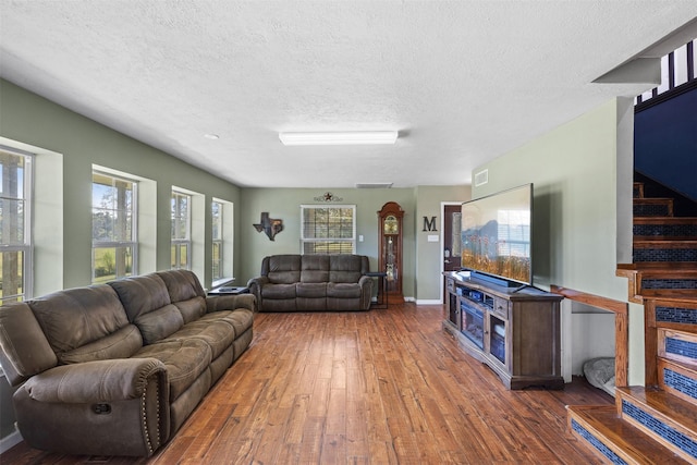 living room with stairs, hardwood / wood-style flooring, baseboards, and a textured ceiling