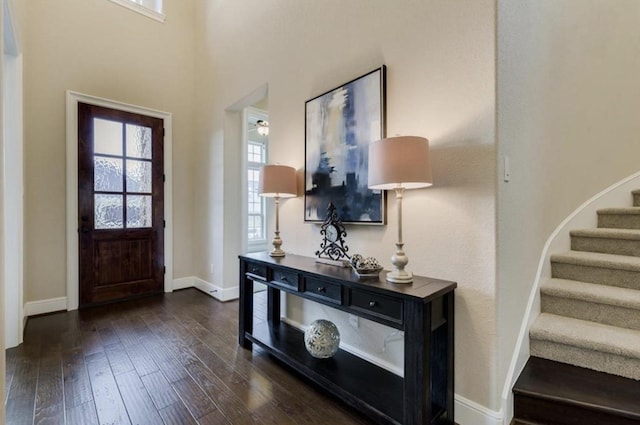 entryway with dark wood finished floors, stairway, and baseboards