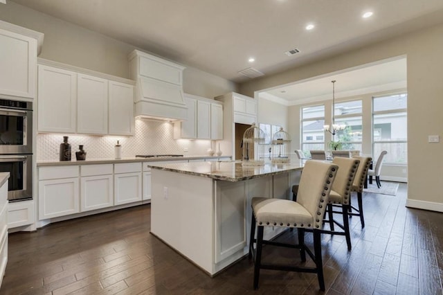 kitchen with stainless steel double oven, backsplash, white cabinetry, and dark wood-style flooring