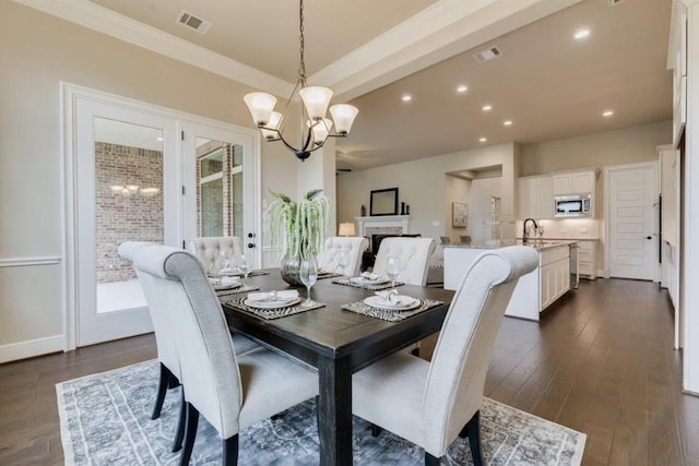 dining area featuring visible vents, a fireplace, an inviting chandelier, and dark wood-style flooring