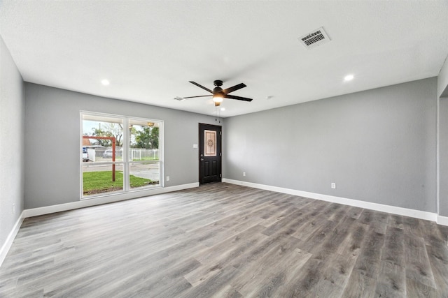 spare room featuring a ceiling fan, wood finished floors, visible vents, and baseboards