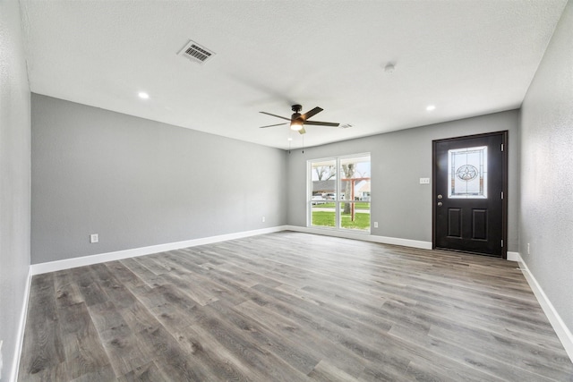 interior space with visible vents, wood finished floors, baseboards, and ceiling fan