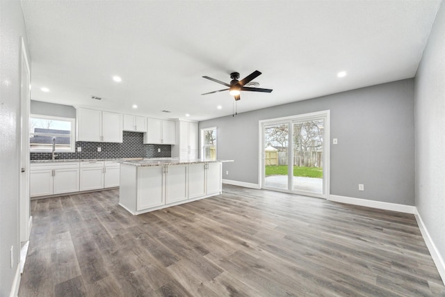 kitchen featuring decorative backsplash, white cabinets, a center island, and light wood finished floors