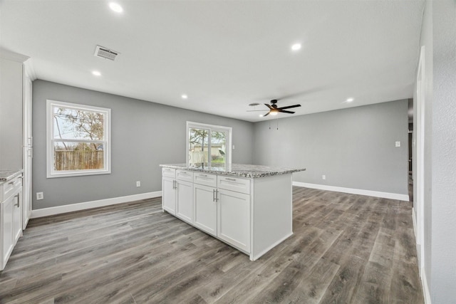 kitchen featuring visible vents, a center island, wood finished floors, and white cabinets