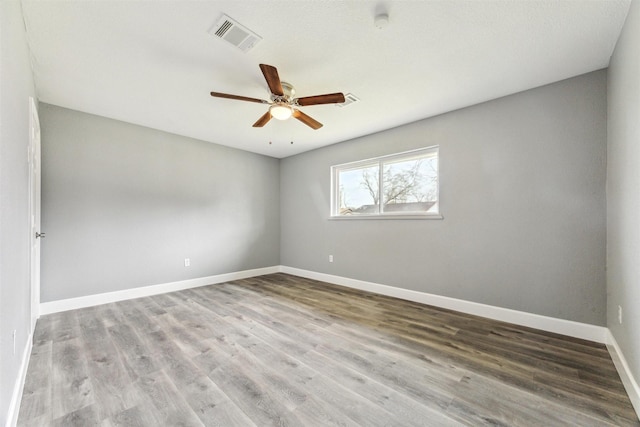 unfurnished room featuring ceiling fan, visible vents, baseboards, and wood finished floors