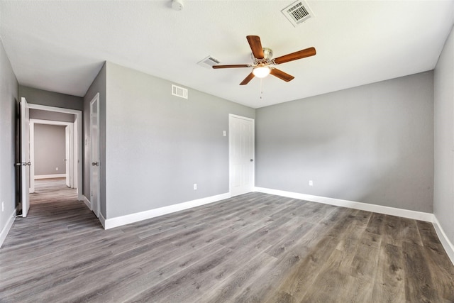 spare room with ceiling fan, wood finished floors, visible vents, and baseboards