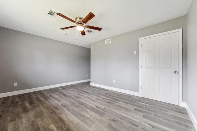 unfurnished room with ceiling fan, wood finished floors, visible vents, and baseboards