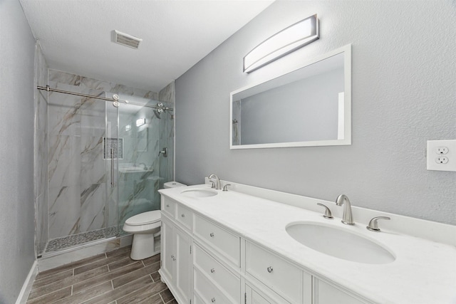 bathroom featuring a sink, a marble finish shower, toilet, and wood tiled floor