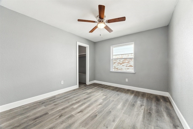 unfurnished bedroom featuring ceiling fan, a closet, baseboards, and wood finished floors