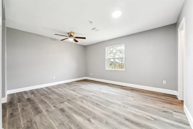 spare room with visible vents, baseboards, wood finished floors, and a ceiling fan