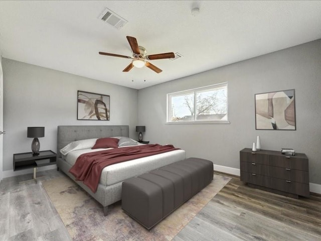 bedroom featuring ceiling fan, visible vents, baseboards, and wood finished floors