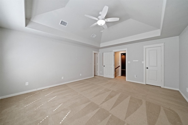 unfurnished bedroom featuring visible vents, light carpet, a raised ceiling, baseboards, and ceiling fan