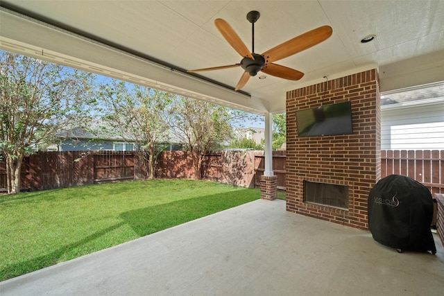 view of patio with grilling area, a fenced backyard, a ceiling fan, and an outdoor brick fireplace