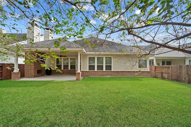 rear view of house with brick siding, a patio area, a yard, and fence