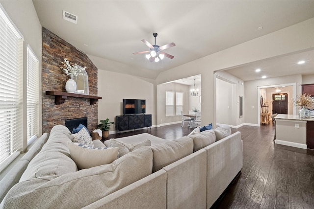 living area featuring a stone fireplace, dark wood-type flooring, baseboards, and visible vents