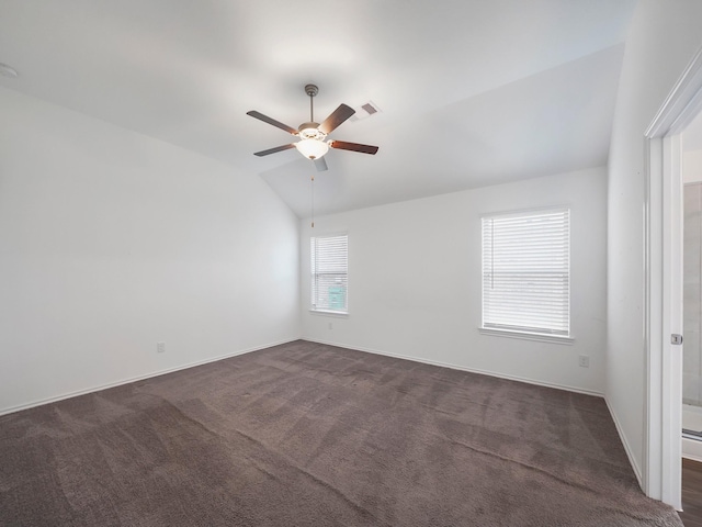 spare room with baseboards, visible vents, lofted ceiling, ceiling fan, and dark colored carpet