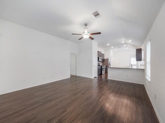 unfurnished living room featuring dark wood-style floors, visible vents, baseboards, lofted ceiling, and ceiling fan