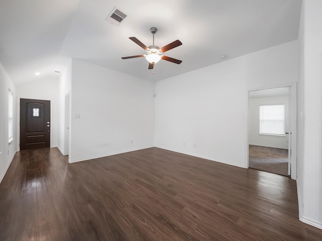 interior space featuring a ceiling fan, visible vents, baseboards, dark wood-style flooring, and vaulted ceiling