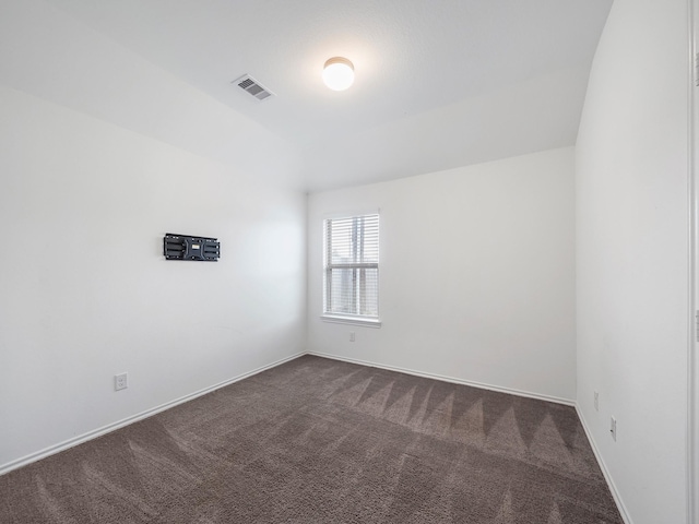 spare room featuring baseboards, visible vents, and dark colored carpet